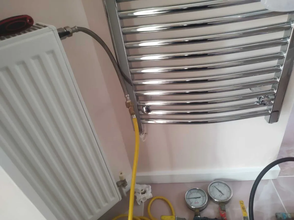 tracer gas hose and dual pressure gauges connected to bathroom radiator during leak detection