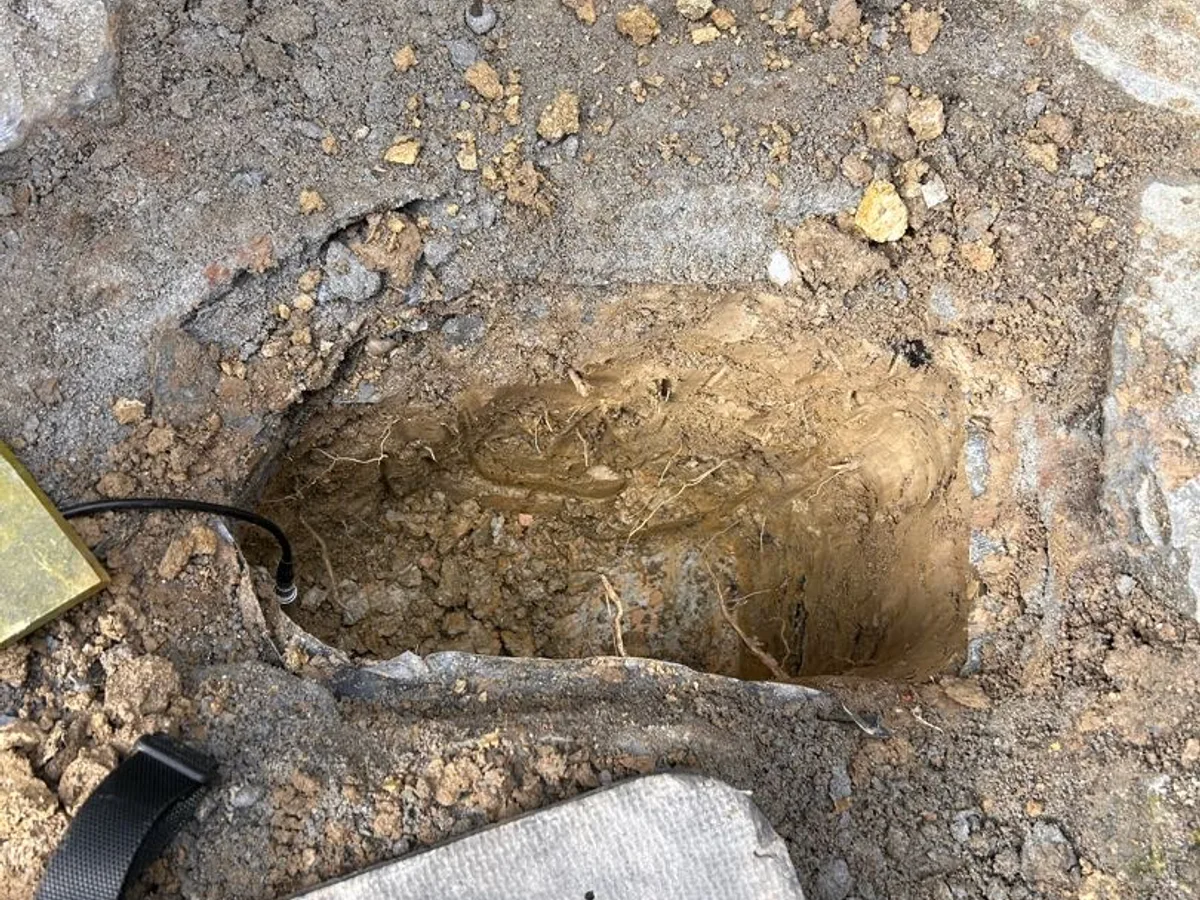 small exploratory excavation in stone paving showing no pipework during leak detection