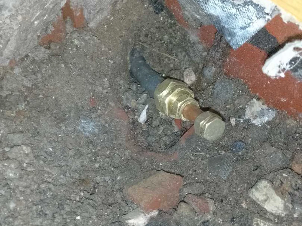 leadlock cap fitting installed on lead mains pipe as repair completed beneath concrete floor