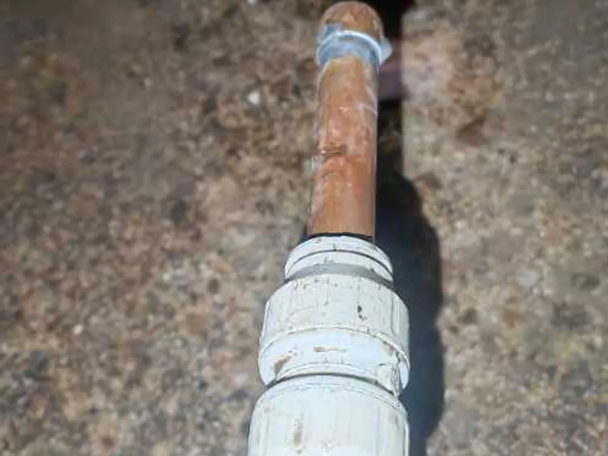 fault identified at pinhole in corroded 15mm copper pipe section removed from beneath floor — leak located at
