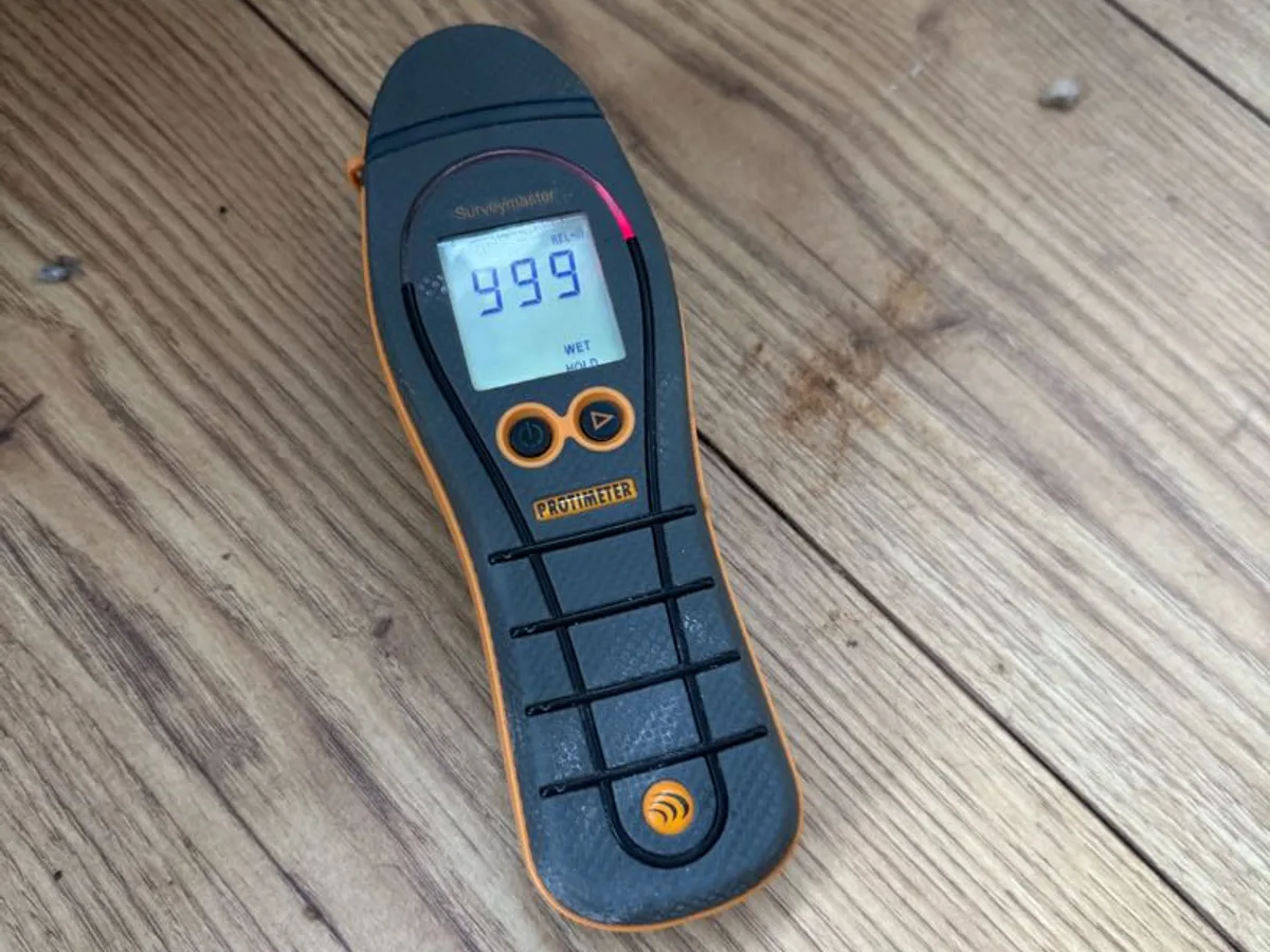 moisture meter reading 999 on saturated floorboard during leak detection