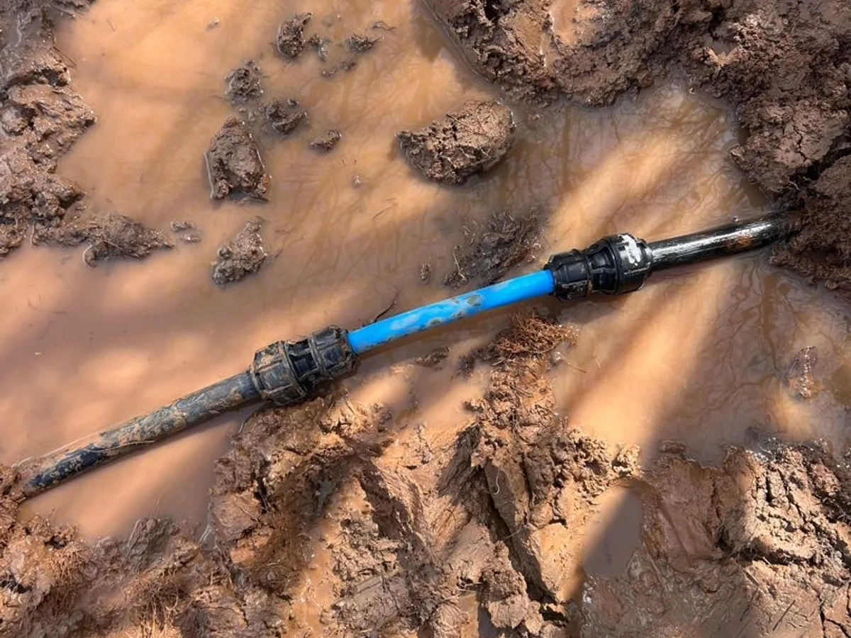 new blue mains pipe section with push-fit couplings installed as repair completed in muddy trench