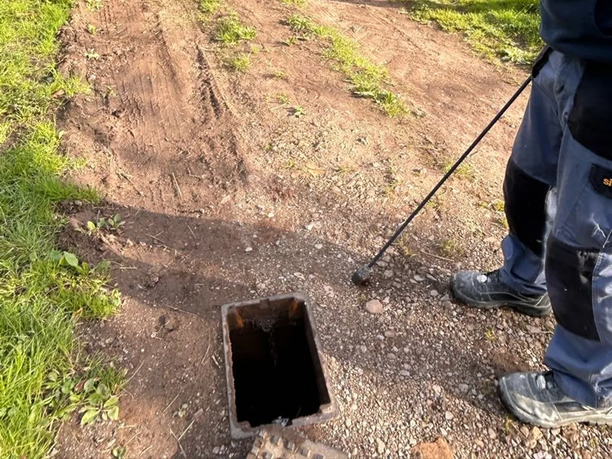 engineer probing stopcock chamber in farm track during leak detection