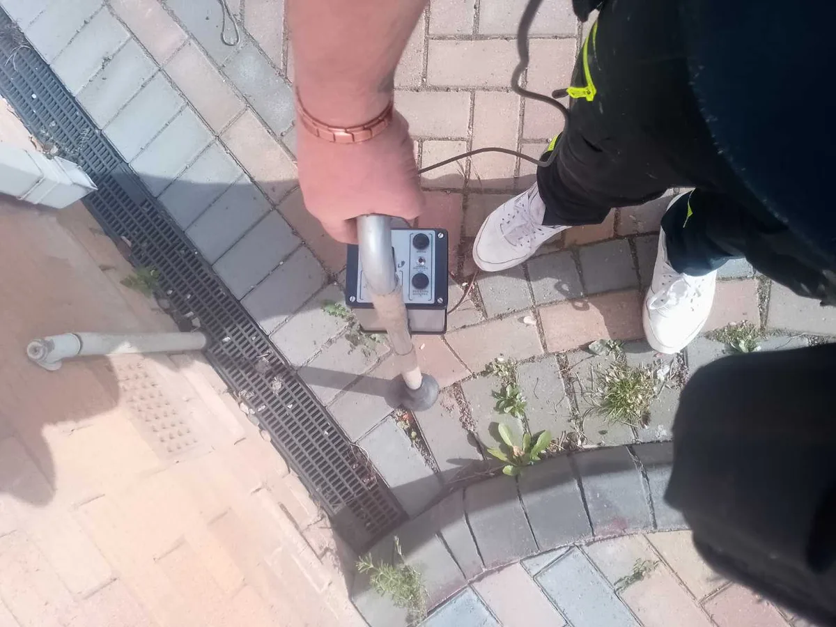 acoustic listening device held over block-paved driveway during leak detection