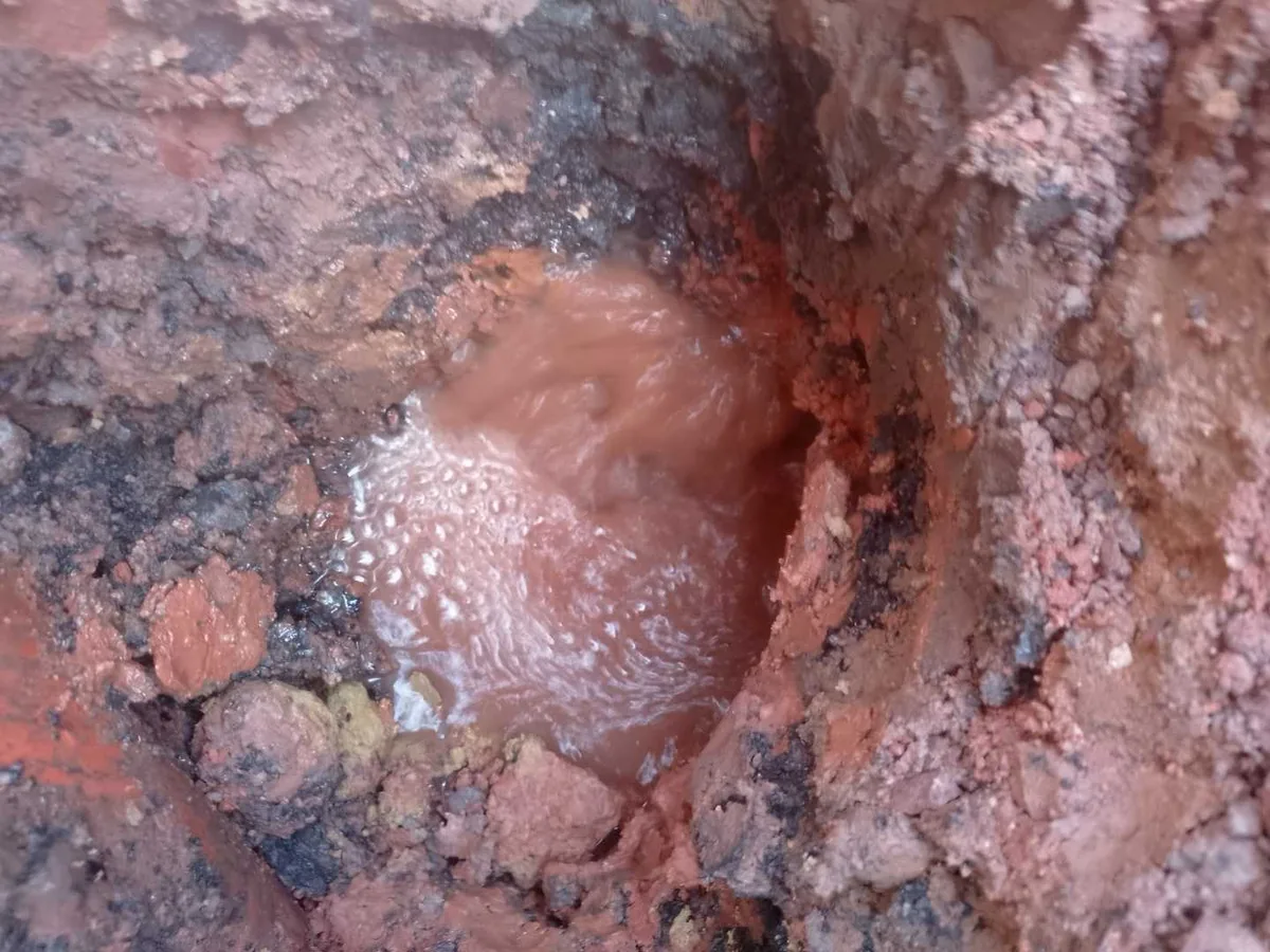 leak located at burst underground water mains pipe with water bubbling from soil