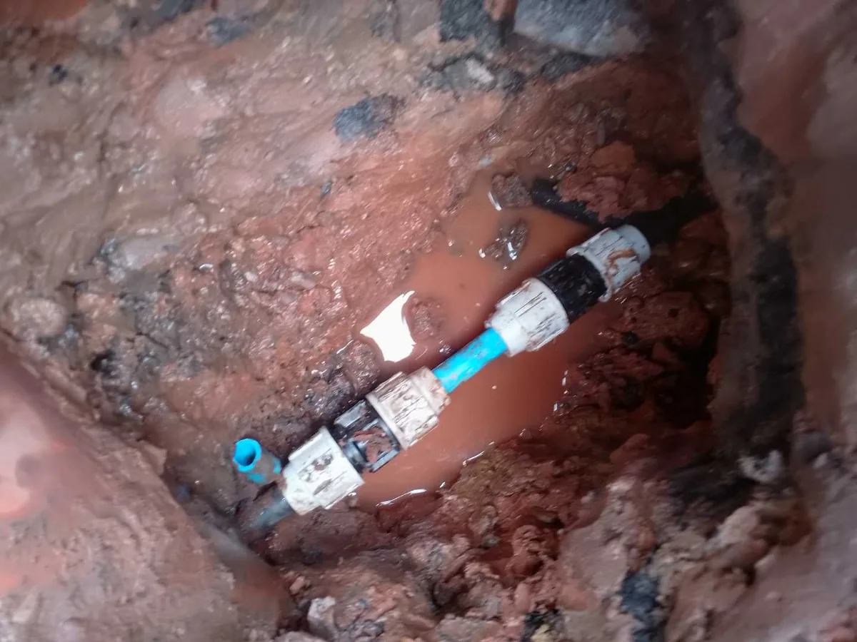 new MDPE pipe section with two couplings installed as repair completed in excavated trench