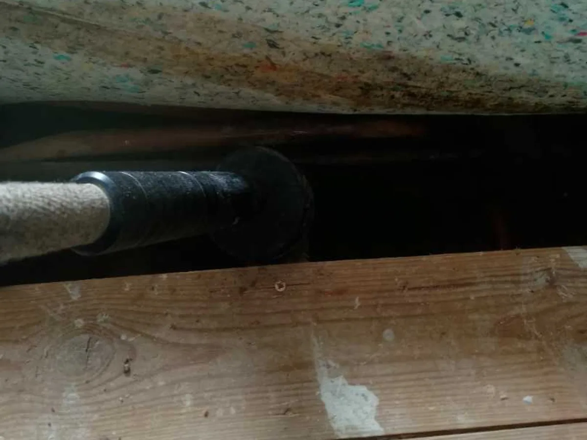 acoustic listening probe inserted into floor void between floorboards during leak detection