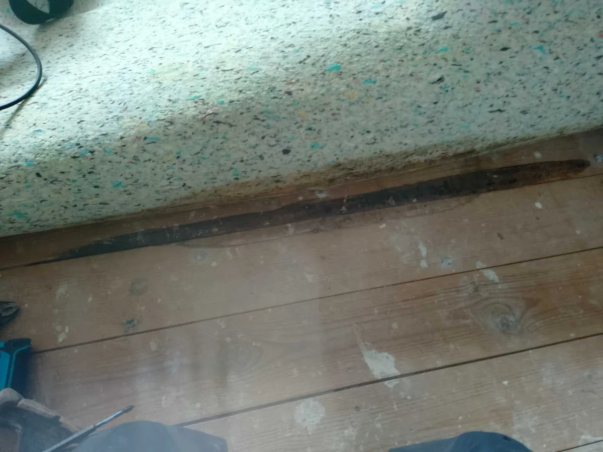 damp staining on floorboards beneath lifted carpet underlay during leak detection