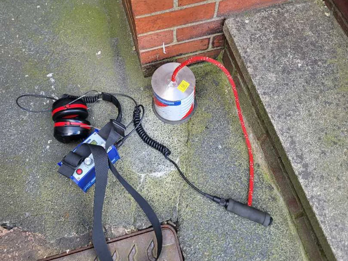 tracer gas cylinder and acoustic listening headset laid out on patio during leak detection