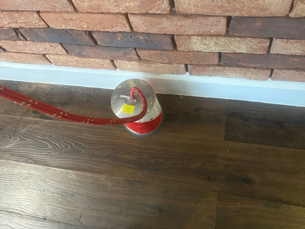 acoustic ground microphone on laminate floor beside brick wall during leak detection