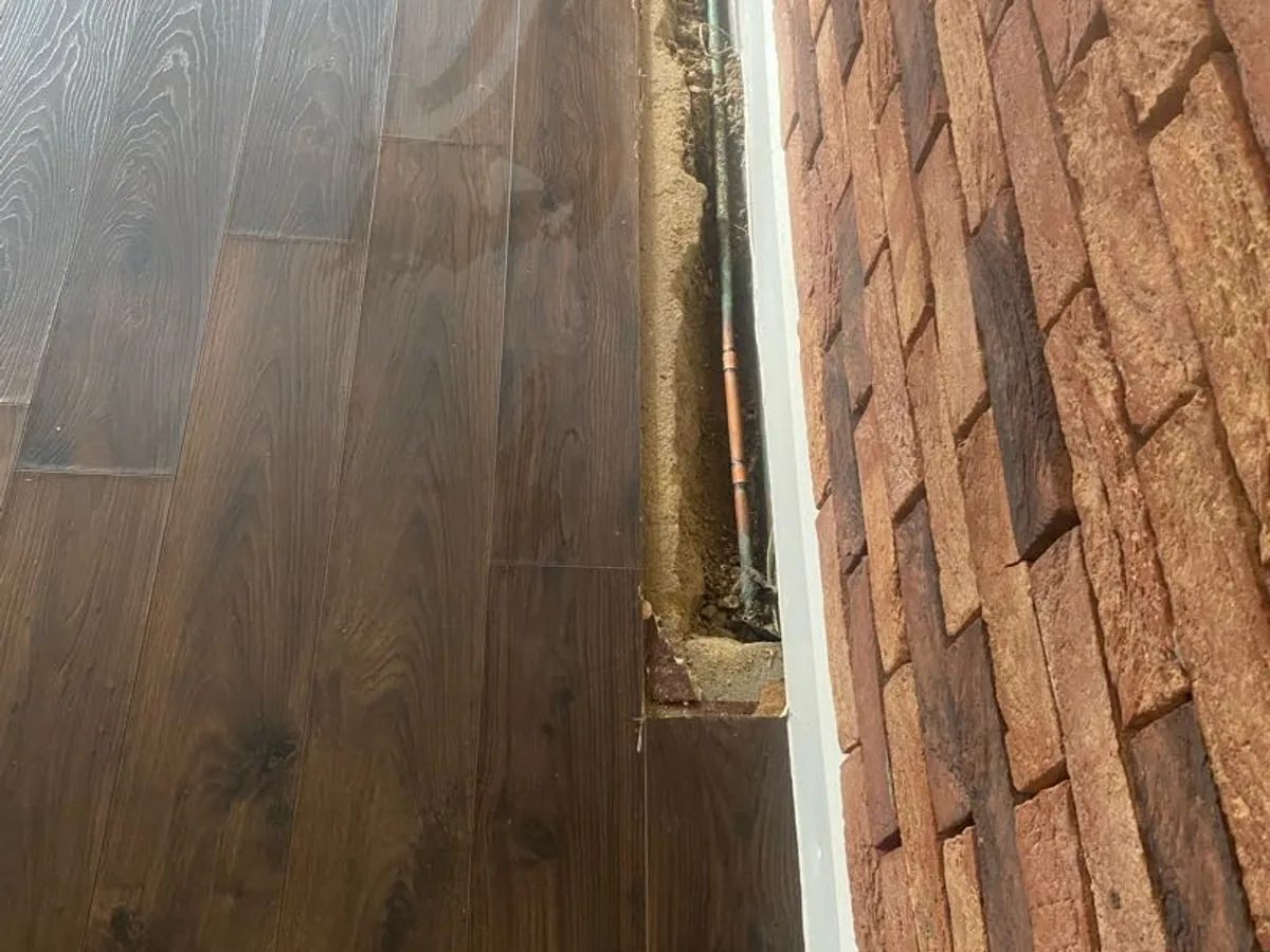 leak found at copper mains pipe exposed in trench cut through lounge floor beside skirting board