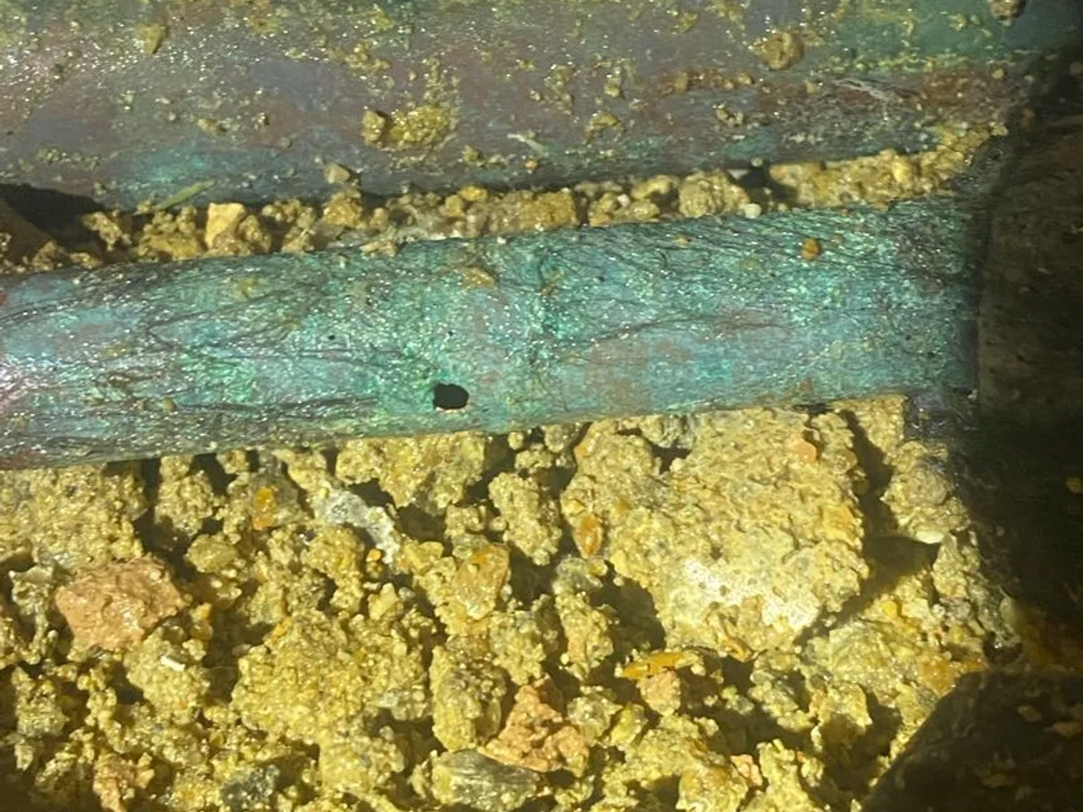 leak located at pinhole in corroded 15mm copper mains pipe exposed beneath lounge screed
