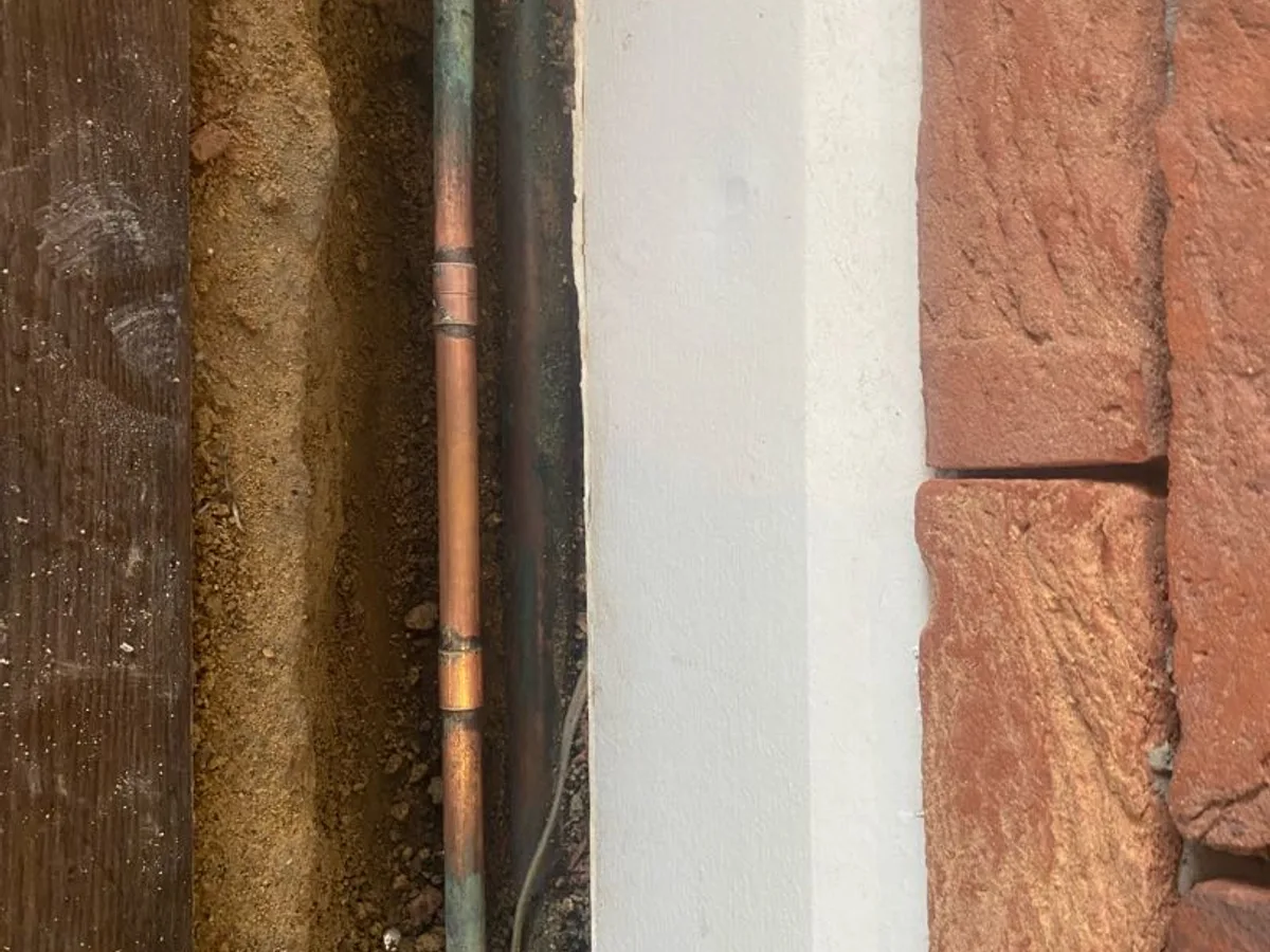 new soldered copper fittings on mains pipe in floor trench as repair completed