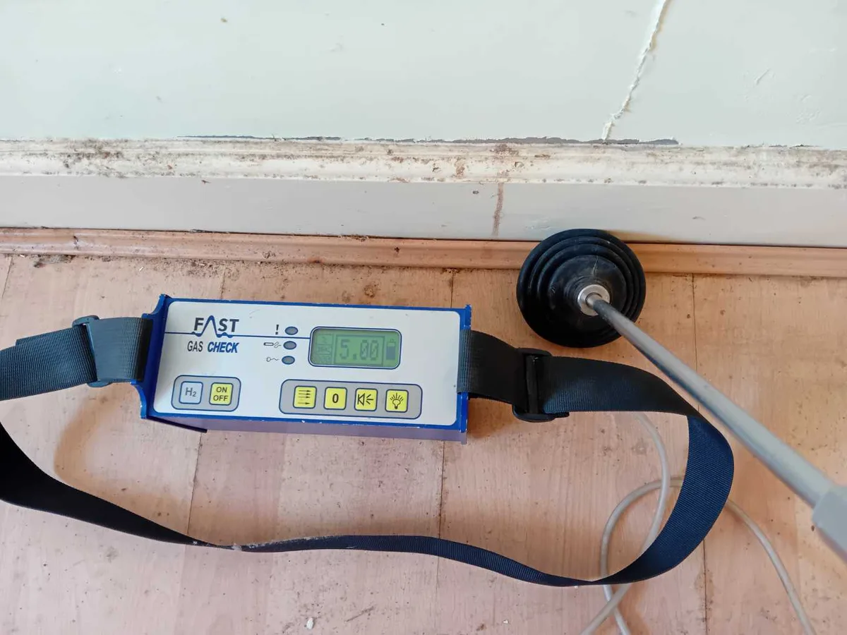 tracer gas detector showing positive reading at kitchen floor level during leak detection